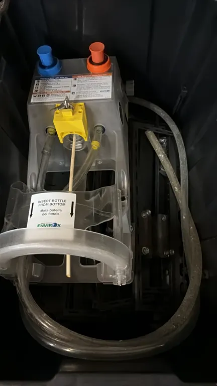 EnvirOx chemical dispenser. Features dual push buttons, bottom bottle insert design, lock with key, and flexible tubing. Storage container not include