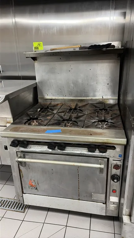 Wolf 6-burner commercial gas range. Features (6) cast iron burner grates, high backriser with top shelf, and oven base with (2) interior wire racks. S