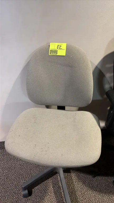Office task chair. Features an armless design with gray fabric upholstery. Mounted on a 5-star rolling caster base.