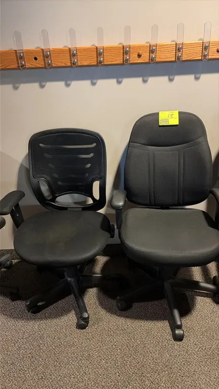 Office chairs. Features black upholstery, including one mesh-back chair with fabric seat and one fully upholstered mid-back chair. Both equipped with