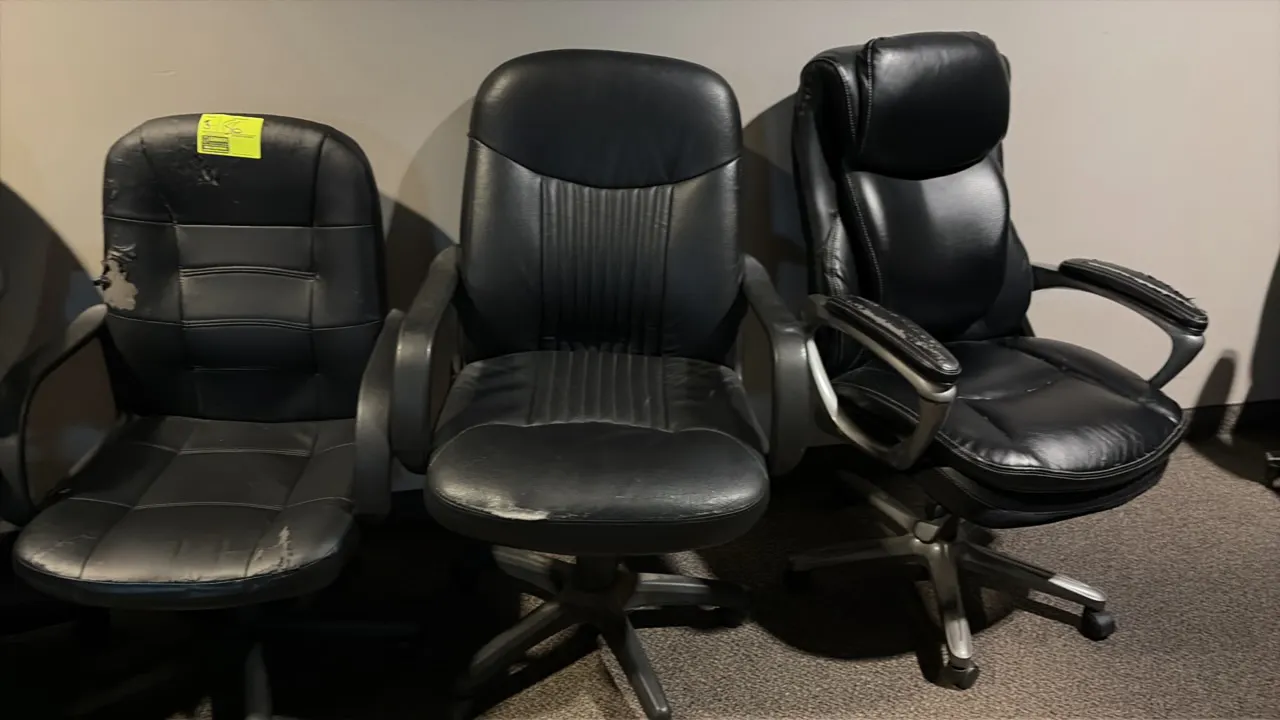 Office chairs. Features black faux leather upholstery, armrests, and swivel seats. Mounted on 5-star bases with rolling casters. Note: Upholstery exhi