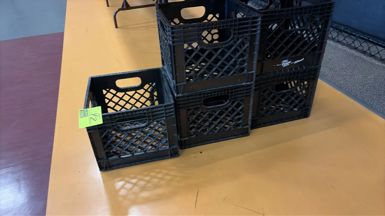 Black plastic milk crates. Features molded plastic construction, open grid pattern, integrated cutout carry handles, and stackable design. Various dai