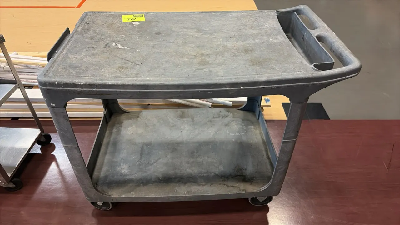 Rubbermaid 2-tier utility cart. Molded plastic construction featuring an integrated push handle, built-in storage compartment, and lower tub shelf. Mo