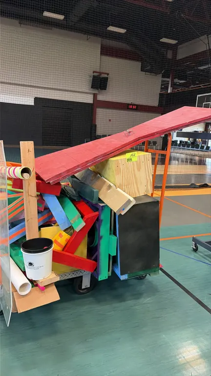 Indoor mini-putt golf course obstacle set. Includes various painted wooden ramps, obstacle blocks, tunnels, and target boxes, along with a roll of gre