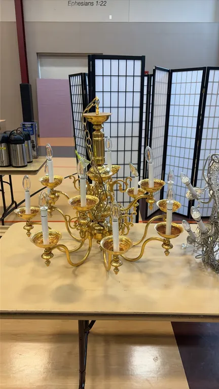 12-light decorative chandelier. Features a polished brass-tone finish, two-tier scrolling arm design, candelabra sockets with faux candle sleeves, han
