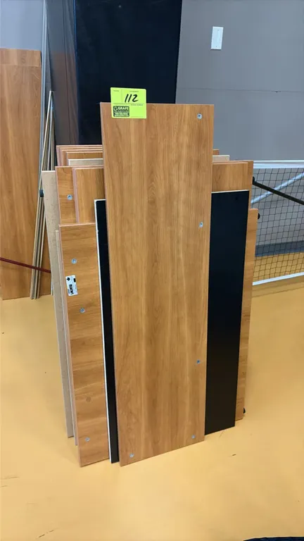 Lacasse wood laminate desk assembly components. Includes an assortment of woodgrain laminate panels with pre-drilled assembly holes, black paneling, a