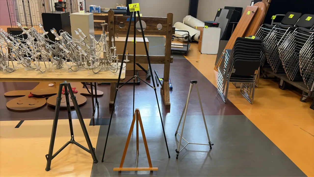 Assorted display sign easels. Features floor-standing and tabletop designs in metal and wood constructions, including a tall folding black metal prese