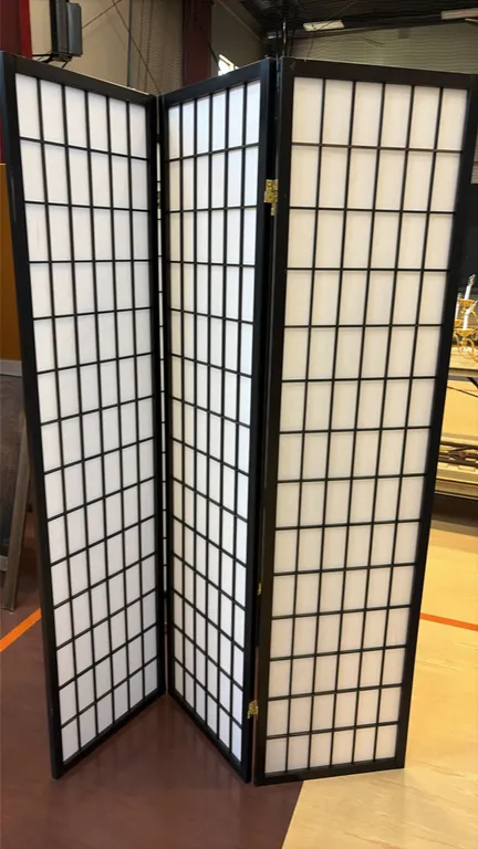 Shoji-style folding room dividers. Features black-finished frames with lattice grid design, white translucent screen inserts, and brass-tone hinges.
