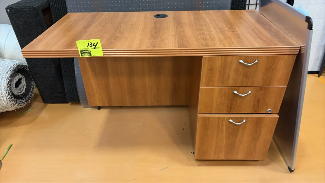 Wood laminate single-pedestal desk. Features a right-hand 3-drawer pedestal with silver-tone pulls, fluted edge profile, and desktop wire grommet. 4'L