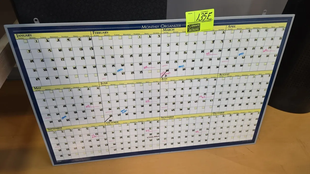 Monthly organizer dry erase board. Features a 12-month annual calendar layout, aluminum frame, and top wall-mounting brackets. 40" x 26".