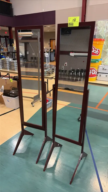 Adjustable full-length clothing mirrors. Features tilting mirror frames with a dark finish. Mounted on freestanding splayed-leg bases.