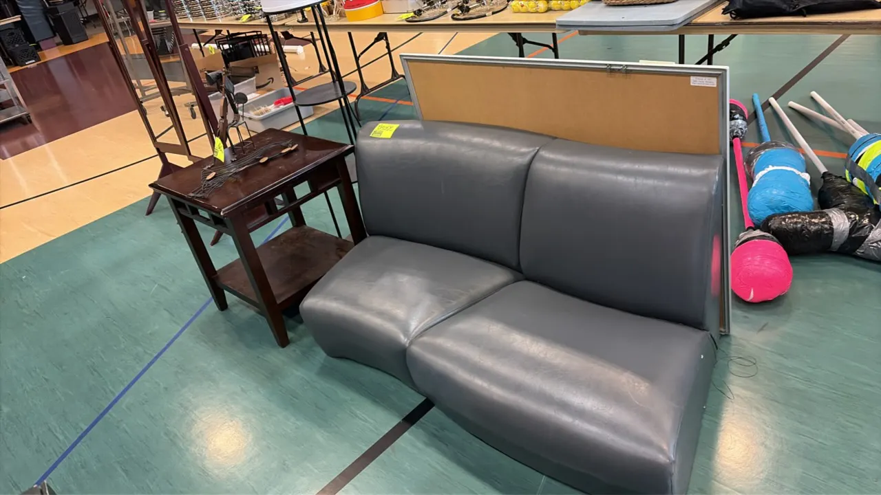 Furniture lot. Includes gray vinyl armless 2-seat couch with contoured seat, dark wood side table with lower shelf, and black multi-tier shelf floor l
