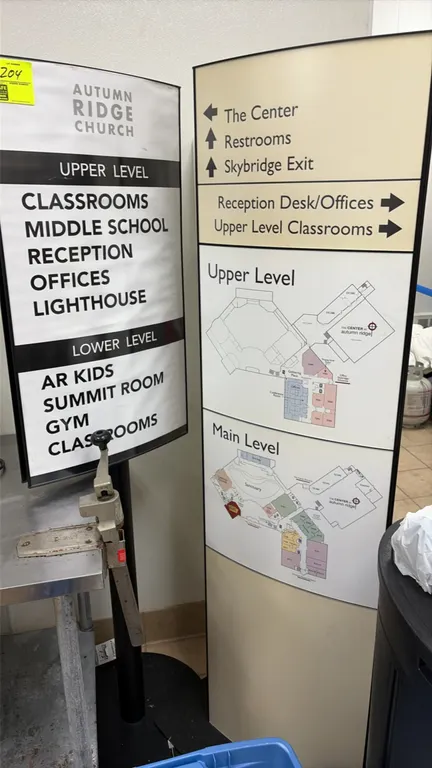 Freestanding directional sign stands. Includes (1) pedestal sign stand with curved frame and round base, and (1) tall freestanding convex directory to