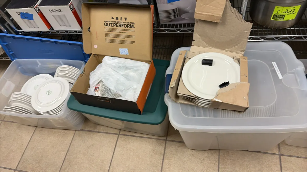 Storage totes of Syracuse China plates, glassware, and rubber bar mats. Features assorted white ceramic dinner and side plates, clear glass items, and