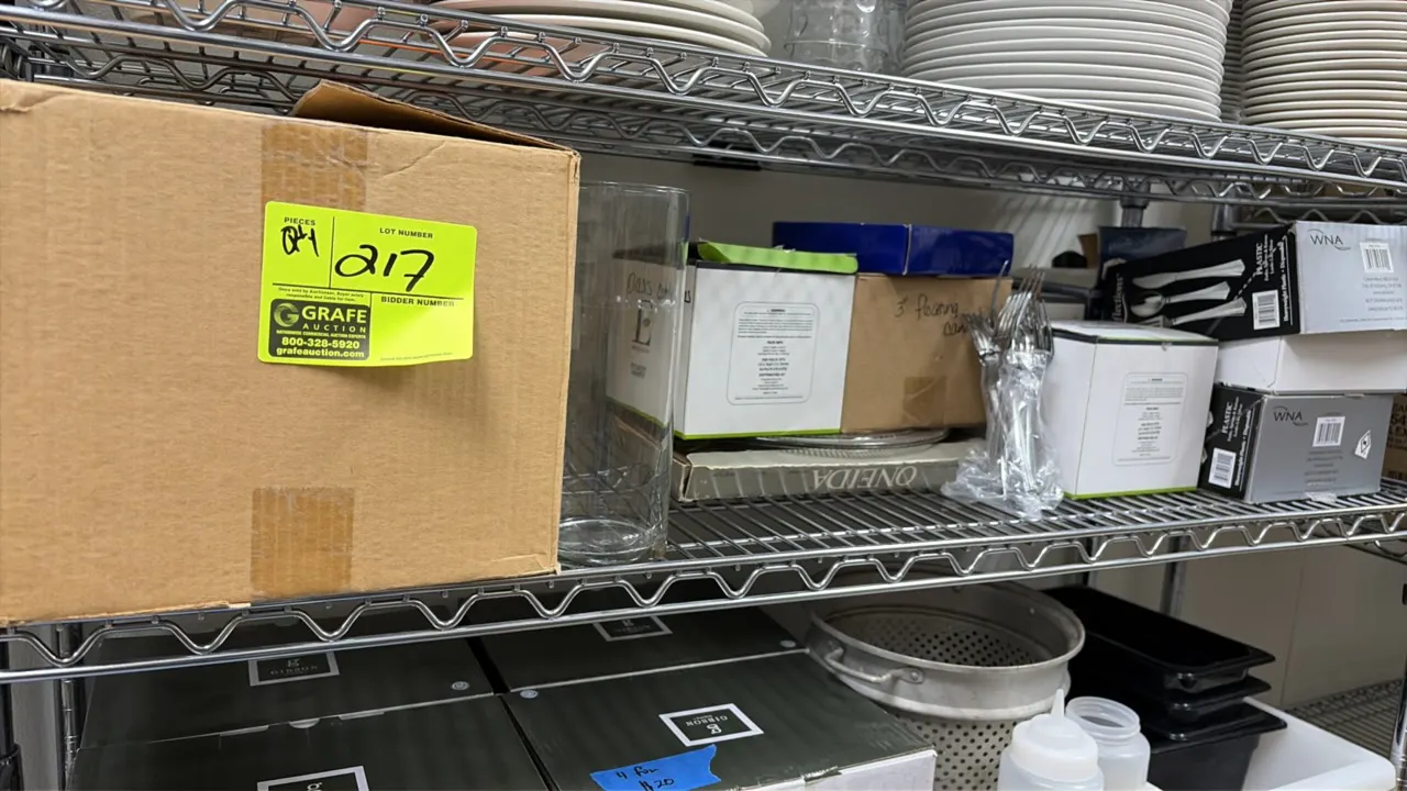 Assorted event supplies lot. Includes glassware, a clear glass cylinder vase, boxed floating candles, and boxed and bagged plastic silverware. Wire sh