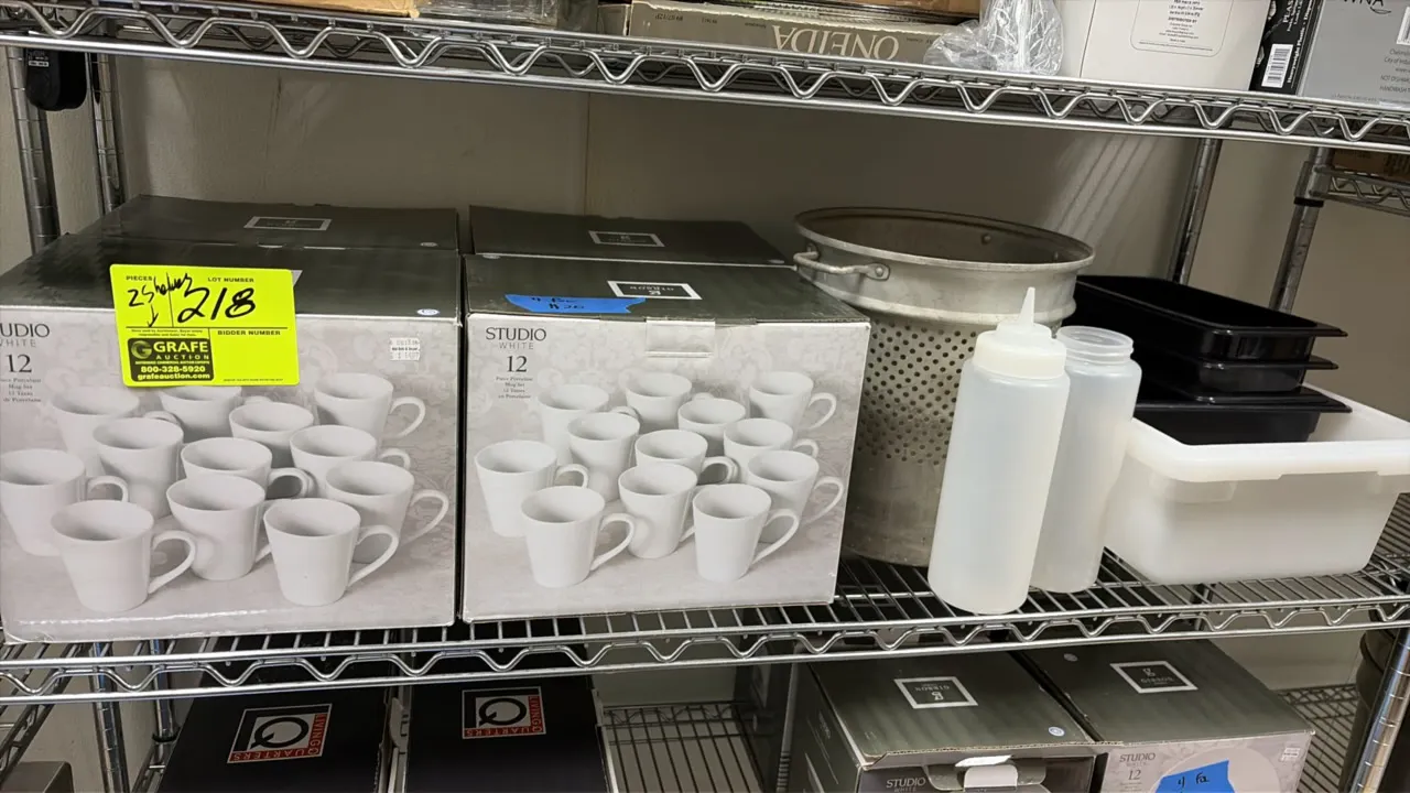 Kitchen and dining smallwares lot. Includes (2) boxed Studio White 12-piece porcelain mug sets, an aluminum colander strainer basket, plastic squeeze