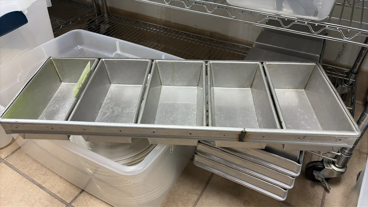 5-loaf strapped baking pans. Features commercial metal construction with five loaf cavities per unit and heavy-duty reinforced framing.