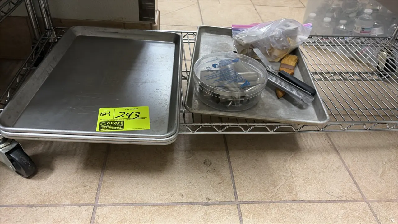 Assorted baking sheet pans and decorating utensils. Includes aluminum sheet pans, assorted pastry piping tips in container, pastry brush, spatula, and