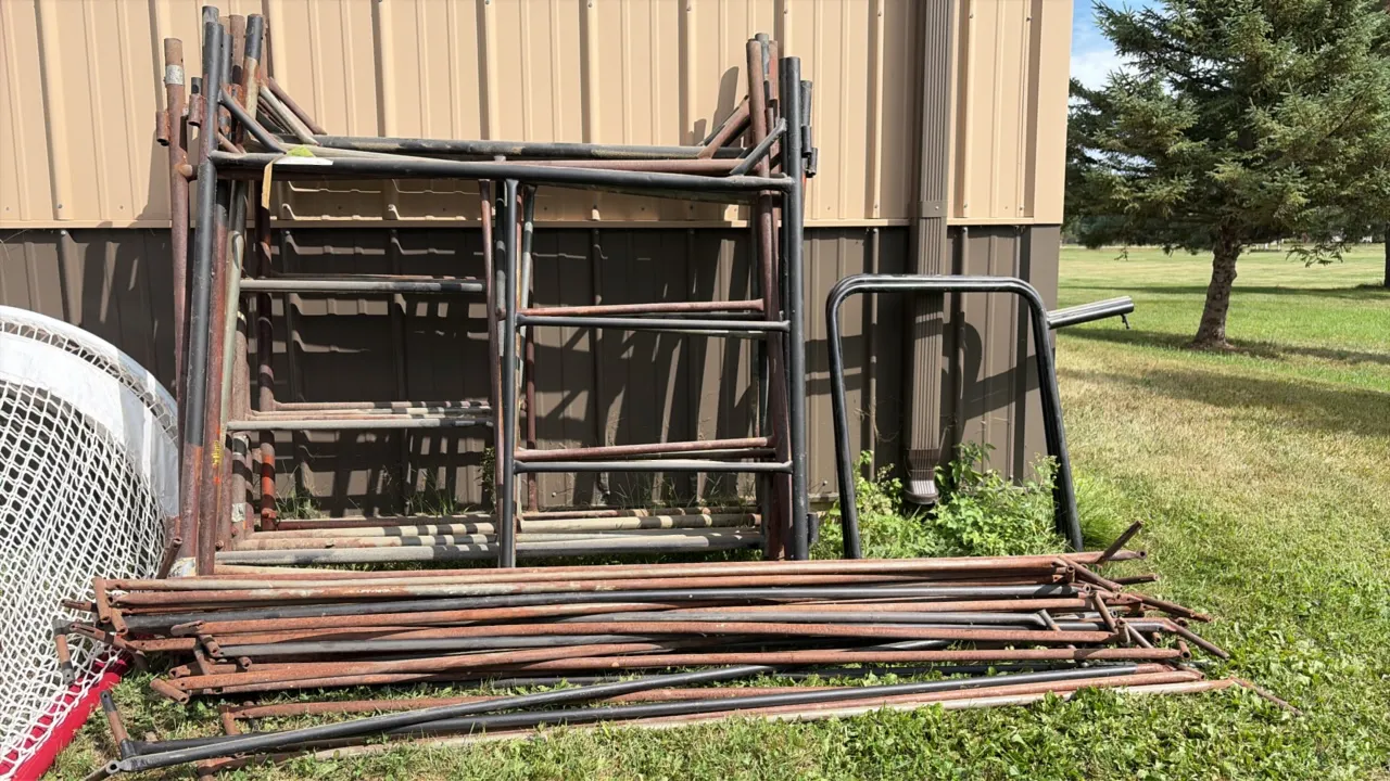 Metal scaffolding lot. Includes steel scaffold end frames, tubular cross braces, and accessory bracket. Tubular steel construction. Netting and backgr