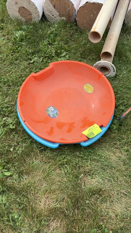Plastic snow saucer sleds. Includes (1) orange and (1) blue saucer sled. Features molded side handles. Background items not included.