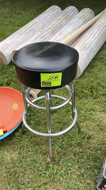 Bar stool. Features a round black vinyl padded seat and chrome-finished tubular metal frame with integrated dual foot rings.
