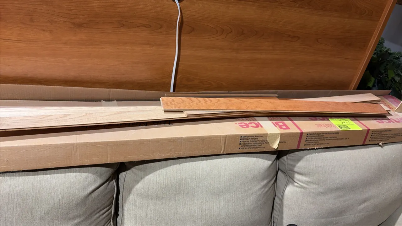 Assorted building and lighting materials lot. Includes a box of Bruce wood flooring planks, fluorescent troffer light fixtures, assorted lighting hous