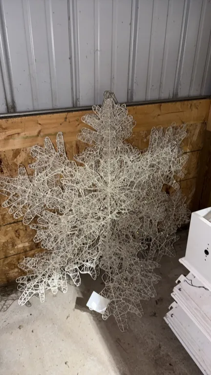 Lighted holiday snowflake display decorations. Features white wireframe construction with woven mesh detailing and integrated string lighting. Designe