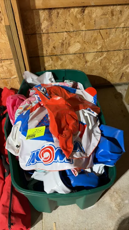 Assortment of inflatable pool toys and floats. Includes WOW brand inflatable water float and various deflated pool floats. Contained in a green plasti