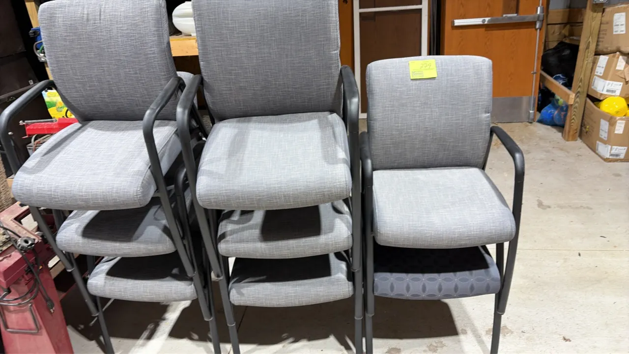Conference chairs. Features gray fabric upholstered seats and backrests, fixed armrests, and black four-leg frames. Note: One chair features patterned
