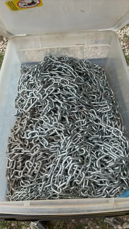 Plastic storage tote containing assorted steel chain. Features galvanized link chain with connecting hardware.