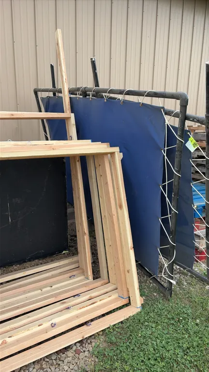 Assorted building materials and fixtures lot. Includes blue vinyl screen laced to pipe frame, wooden framing, white 6-panel interior door, corrugated
