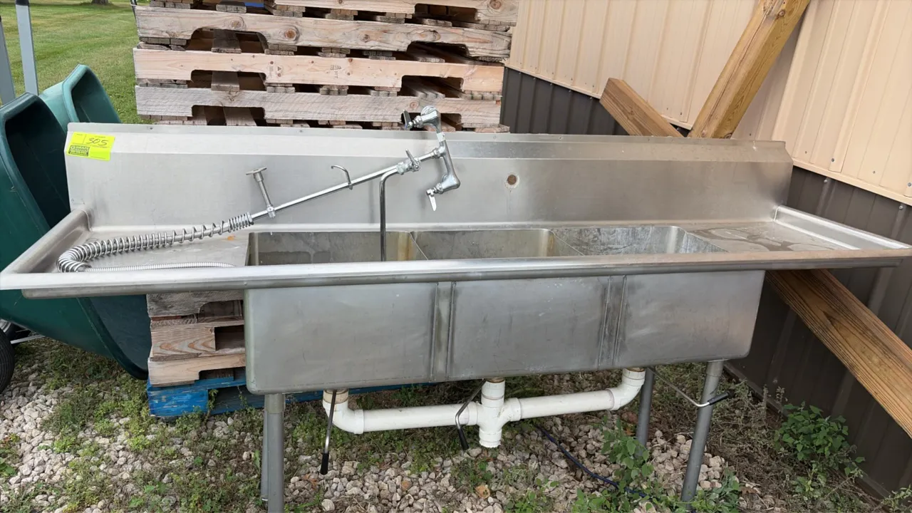 Stainless steel 3-compartment sink. Features left and right drainboards, integrated backsplash, splash-mount pre-rinse faucet assembly, and lever wast