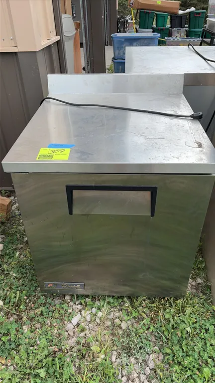 True TWT-27 single-door worktop refrigerator. Features stainless steel exterior, rear backsplash, recessed door handle, and self-contained refrigerati