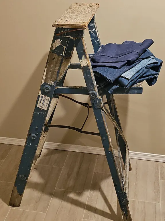Wooden Step Ladder with Paint Splatter and Folded Denim Fabrics