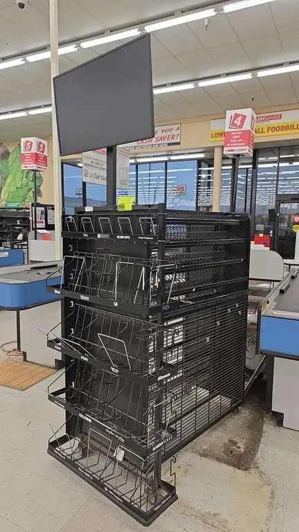 Portable metal candy and magazine merchandiser display rack. Features multi-tier angled wire shelving, end-cap magazine pocket racks, and a 2'5" mount