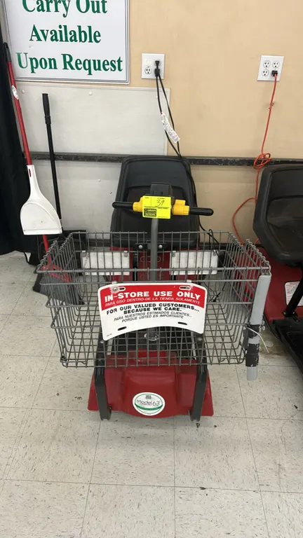 Mart Cart Model 63 motorized shopping cart. Features front wire basket, molded plastic seat, handlebar throttle controls, and integrated power chargin