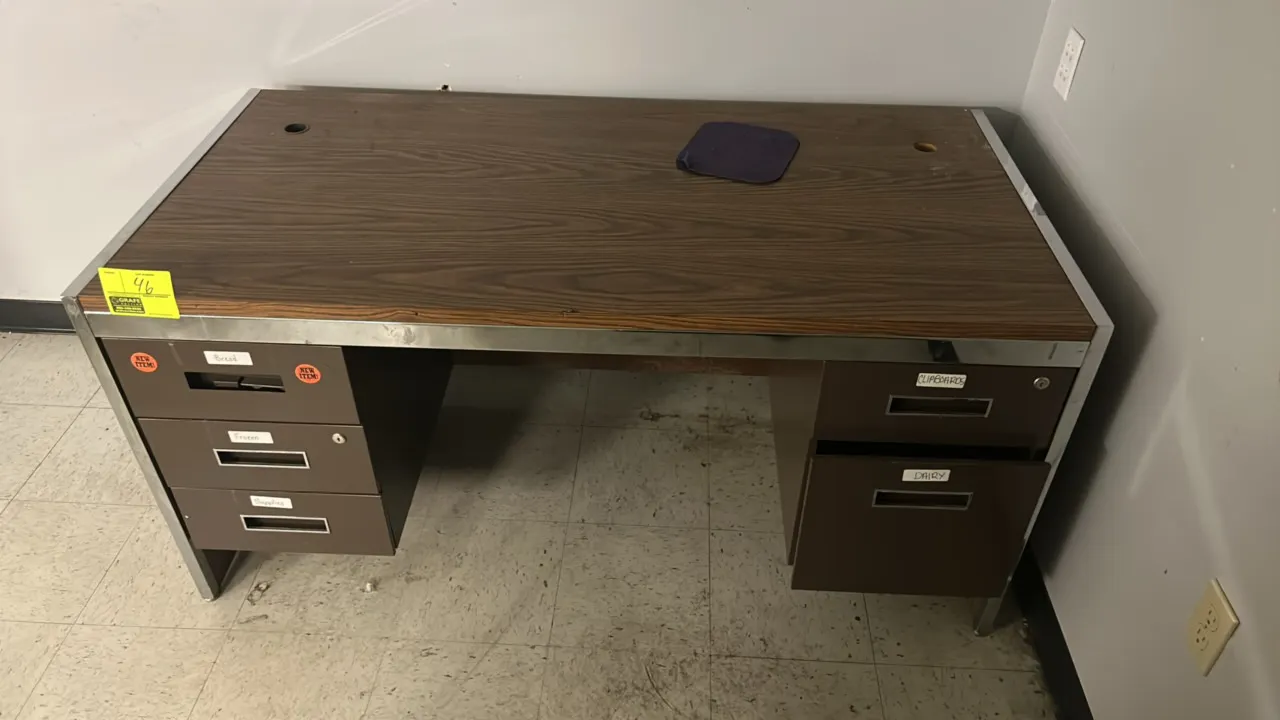 Metal double-pedestal desk. Features a woodgrain laminate top and side panels, chrome-tone trim, dual cord management grommets, a left 3-drawer pedest