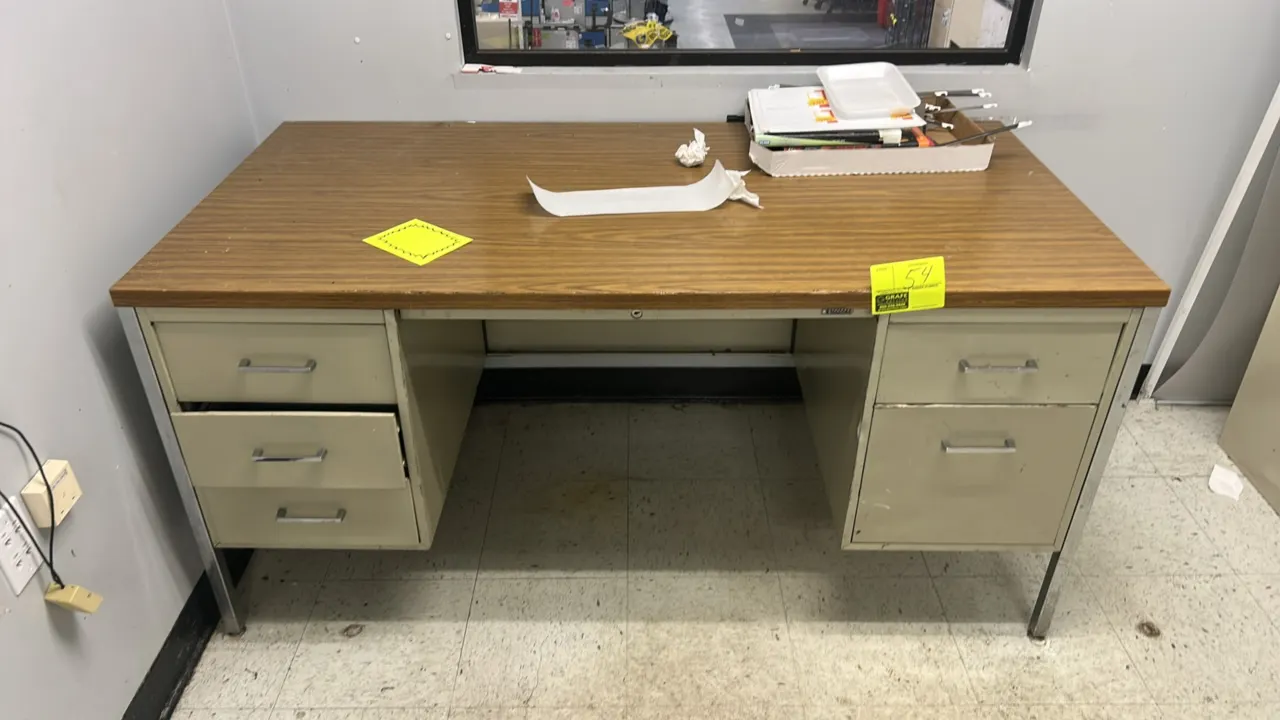 Double-pedestal metal office desk. Features a woodgrain laminate top, tan metal base, chrome legs, and 5 drawers across two pedestals. 60" x 30". Cont
