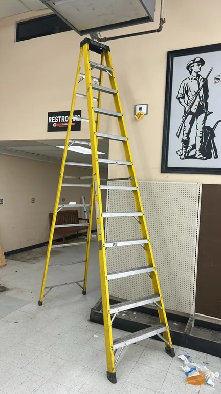 12' fiberglass stepladder. Features yellow fiberglass side rails, aluminum steps, metal spreaders, and a molded top cap.