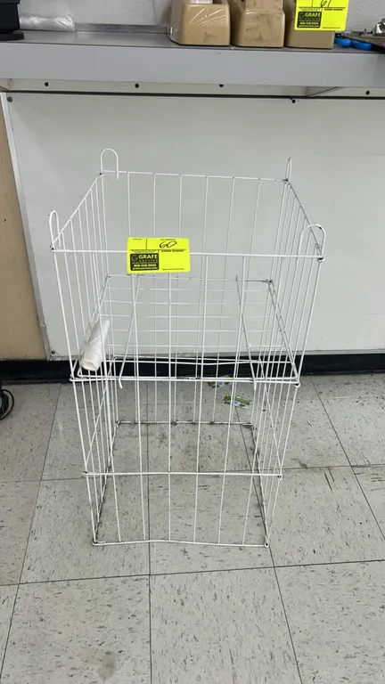 Metal wire dump bin display basket. Features white coated wire construction, an adjustable false-bottom shelf, and a collapsible design.