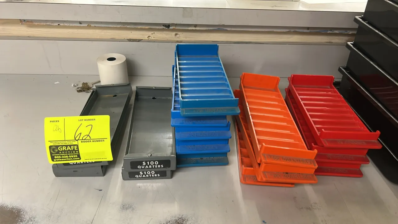 Assorted metal and plastic coin storage trays. Includes gray metal quarter trays and color-coded molded plastic trays for pennies, nickels, and quarte