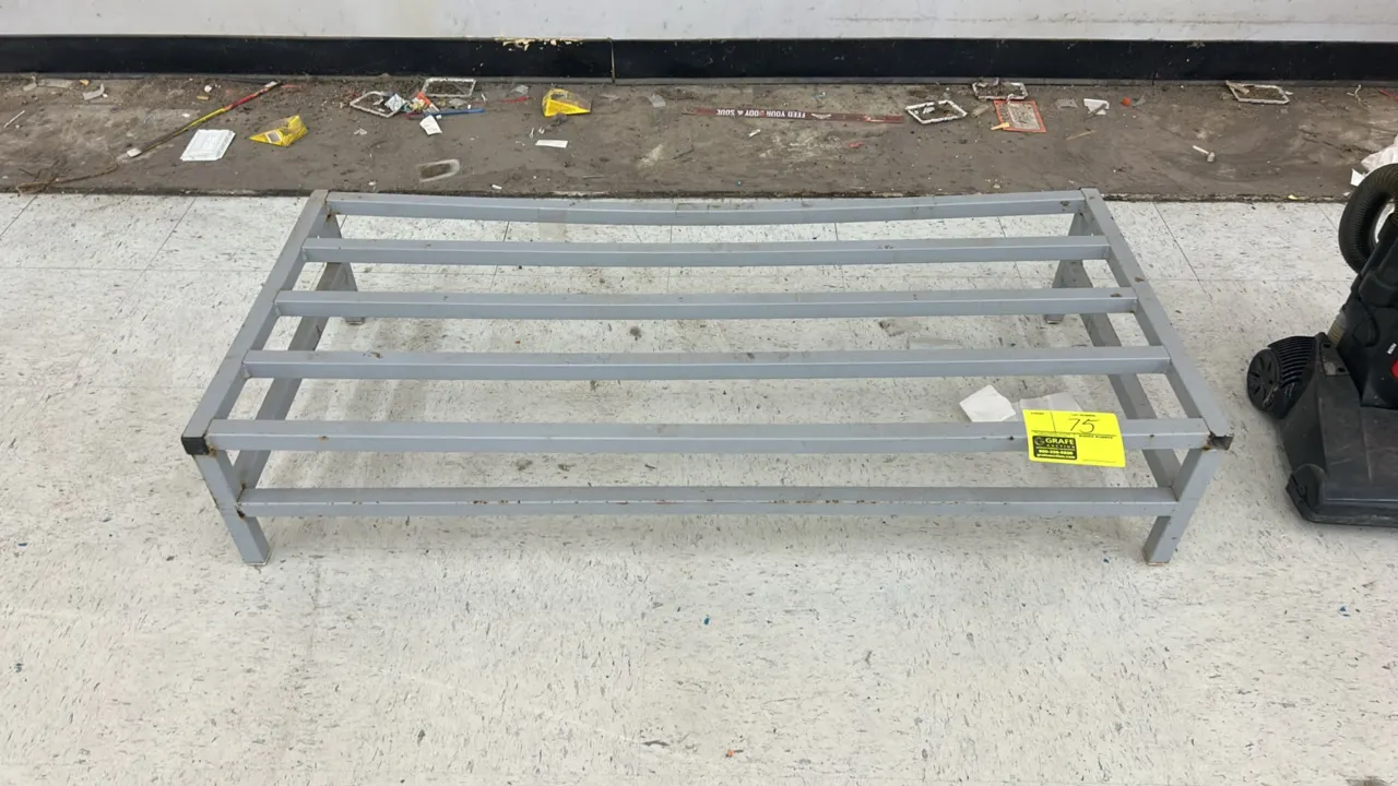 Metal dunnage rack. Features welded tubular metal construction, slotted top surface, and a gray finish. 4'L.