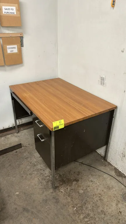 Metal single-pedestal desk. Features a woodgrain laminate top, right-hand 2-drawer pedestal, center pencil drawer, dark-finish metal frame, and chrome