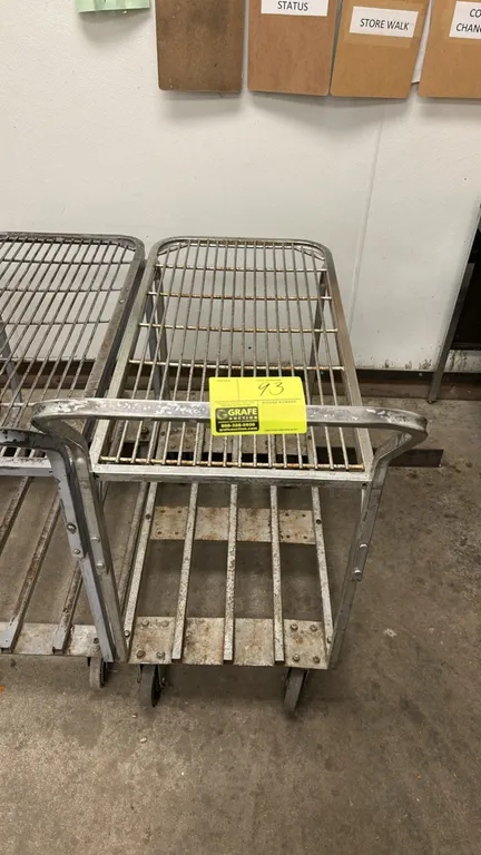 Metal 2-tier utility cart. Features a wire grid upper shelf, slatted metal lower deck, and integrated push handle. 3'L. Mounted on casters.