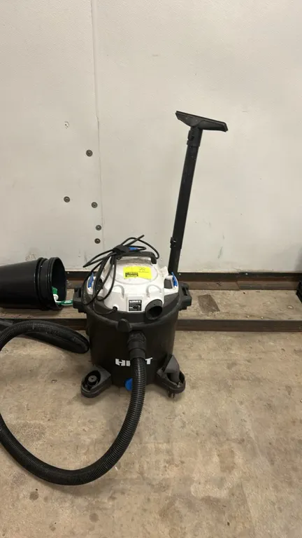 Hart VOC1001PF 10-gallon wet/dry vacuum. Features a plastic drum, top carry handle, blower port, flexible hose, extension wand, and attachment nozzles