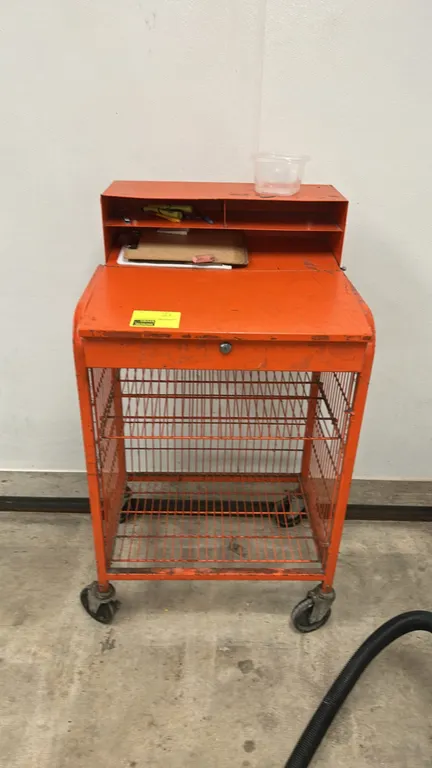 Portable metal workstation cart. Features a slanted writing surface with key lock, upper organizer compartments, and a lower wire mesh storage compart