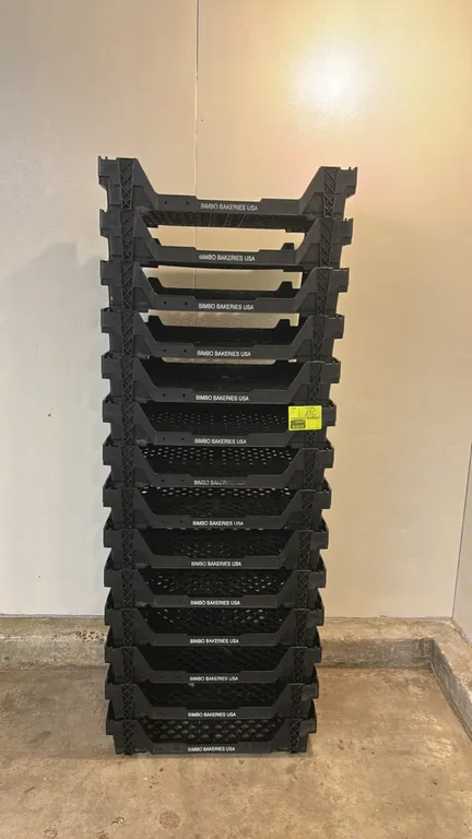 Poly bakery crates. Features black molded plastic construction, vented bottom and side walls, integrated carry handles, stackable nesting design, and