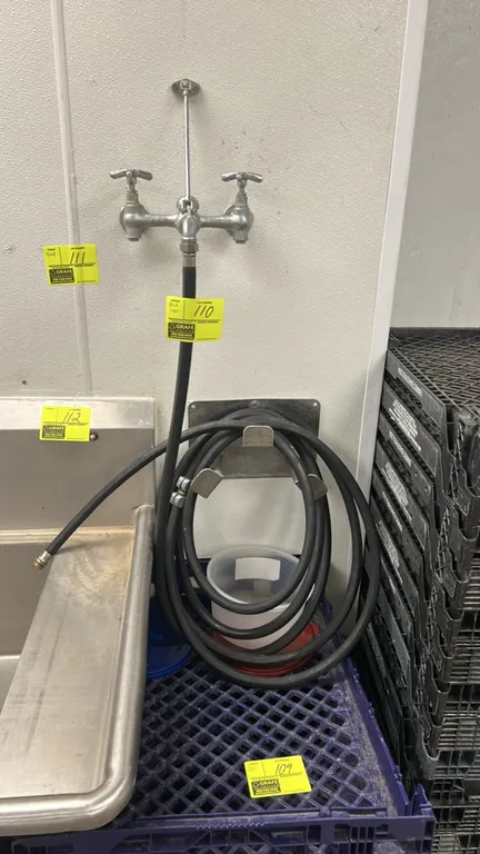 Black rubber washdown hose. Includes wall-mounted stainless steel hose hanger bracket. Features a threaded brass end fitting. Note: Faucet, sink, and