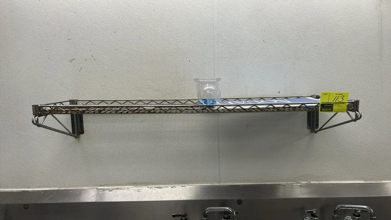 4'L metal wire wall shelf. Features wire grid construction and includes (2) wall-mounting brackets. Note: Shows visible surface rust. Contents, sink,