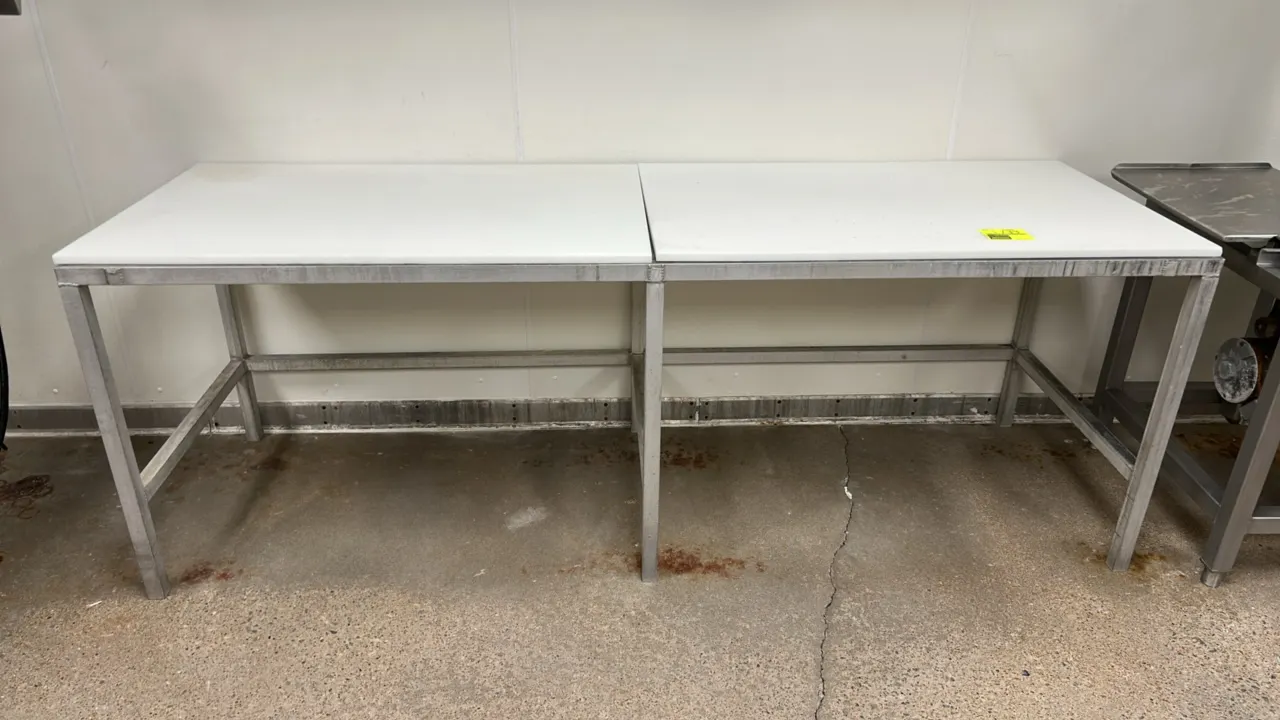 Stainless steel work table with poly top. Features a 2-piece white poly cutting board surface and stainless steel frame with lower cross-bracing. Dime